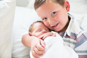 big brother on bed with little brother newborn