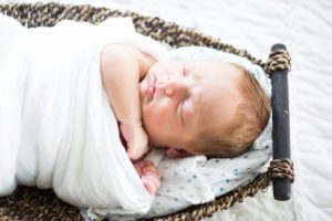 newborn on bed in basket