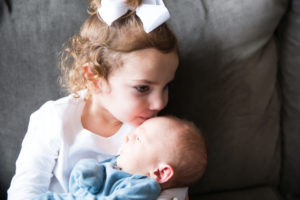 big sister kissing baby brother forehead