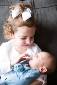 big sister holding baby brother on couch