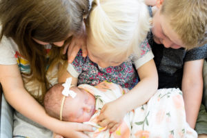 siblings holding newborn baby