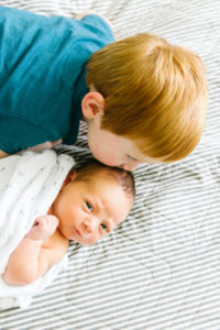 big brother kissing newborn baby's head