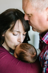 dad kissing mom kissing newborn baby