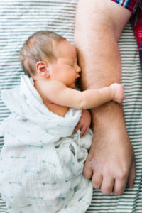 newborn holding dad's arm