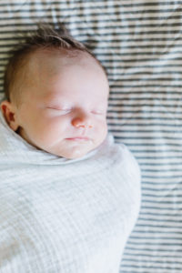 newborn baby boy sleeping swaddled on the bed