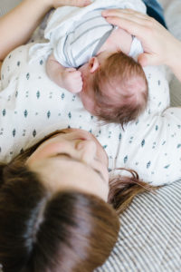 mom snuggling baby boy on her chest on the bed