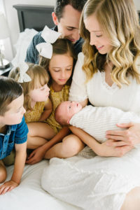 family adoring baby brother in mom's arms