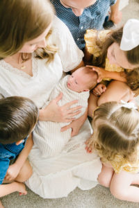 family looking at newborn brother in their own home