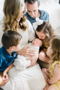 family photo looking at newborn on the floor of home