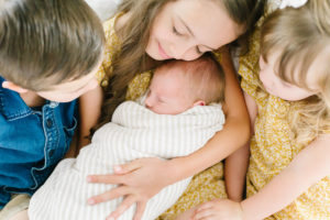 siblings holding new baby brother