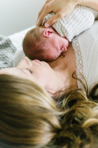 newborn baby boy laying on mom's chest on bed