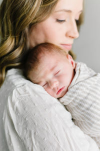 mom snuggling new baby boy on her shoulder