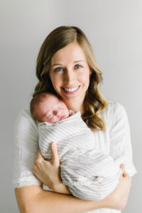 mom holding new baby boy looking at the camera