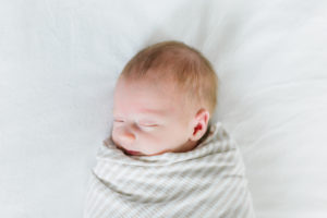 sleeping newborn baby swaddled on bed