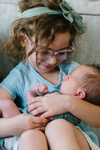 Sister holding newborn baby brother