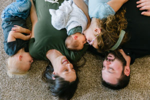Family on the floor while sister kissing newborn baby brother