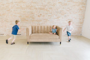 older brothers running around couch with little brother