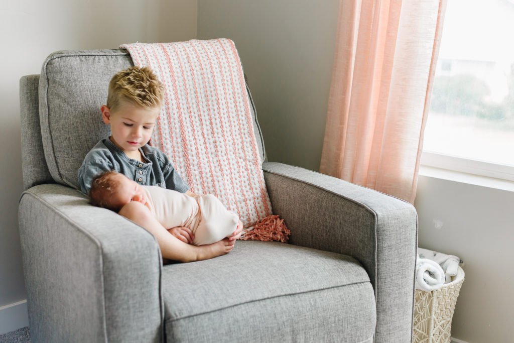 older brother looking at newborn sister in in-home newborn session